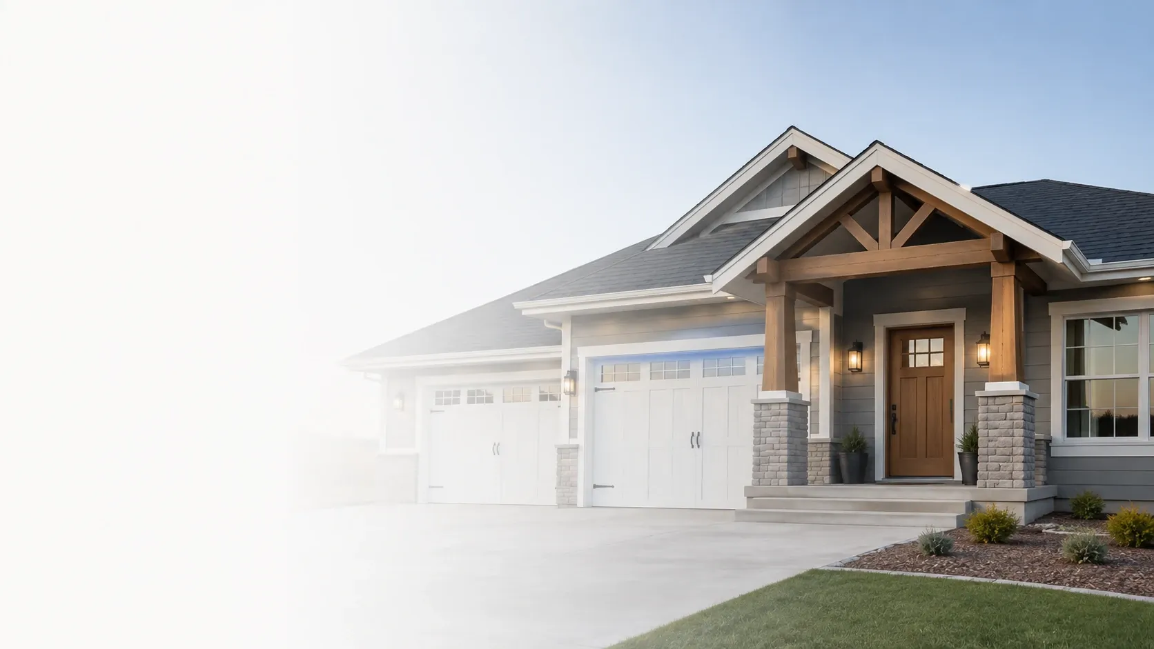 A craftsman-style home with a stone porch and two garage bays on a bright morning